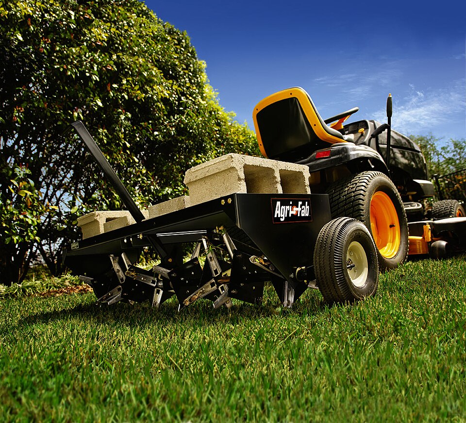 Tow-behind plug aerator with hollow tines, pulled by a lawn tractor